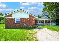 Charming brick home with a covered front porch, grassy yard, and sunny sky at 1509 E Centennial Ave, Muncie, IN 47303