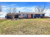 Charming single-story home with a cozy front porch and inviting orange door, surrounded by a well-maintained lawn at 15415 E 146Th St, Noblesville, IN 46060