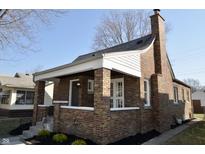 Quaint brick home with a charming front porch and well-maintained landscaping at 729 N Chester Ave, Indianapolis, IN 46201