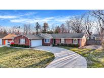 Charming brick home featuring a well-manicured lawn and an inviting, curved driveway at 8425 Bishops Ln, Indianapolis, IN 46217