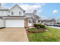 Charming townhome with a brick facade, attached garage, and well-maintained front lawn with garden beds at 915 Prestwick Dr # D, Indianapolis, IN 46214