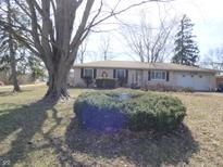 Charming single-story home featuring a two-car garage and mature landscaping at 9395 E Thompson Rd, Indianapolis, IN 46239