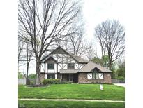 Charming Tudor-style home with brick facade, manicured lawn and a freshly paved walkway leading to the front door at 1728 Timber Heights Dr, Carmel, IN 46280
