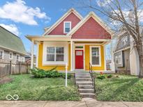 Charming home with a red door, yellow siding and red shingles on the upper level at 251 Hendricks Pl, Indianapolis, IN 46201