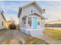 Charming home featuring gray siding, a bright blue front door, and a cozy covered porch, with a driveway leading to the street at 411 W Memorial Dr, Muncie, IN 47302