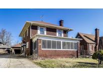 Two story brick home featuring a covered porch and a well-maintained lawn at 518 Central S Ct, Indianapolis, IN 46205