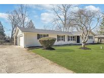 Charming single-story home with a manicured lawn and a long driveway leading to an attached garage at 5540 Broadmoor Plz, Indianapolis, IN 46228