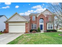 Charming two-story brick home boasts a manicured lawn, attached garage, and inviting blue front door at 6806 Powder Dr, Indianapolis, IN 46259