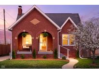 Charming brick home with arched porch, manicured lawn, and flowering tree at twilight at 1014 Shannon Ave, Indianapolis, IN 46201