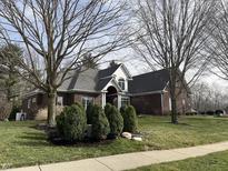 Charming brick home featuring a well-manicured lawn, mature trees, and covered front porch at 10448 Oak Ridge Dr, Zionsville, IN 46077