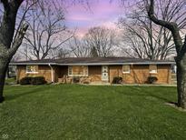 Charming single-story brick home with a spacious front yard and mature trees under a twilight sky at 3008 Nichol Ave, Anderson, IN 46011