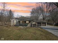 Charming single-story home featuring a covered porch and a detached two-car garage, set against a vibrant sunset sky at 4709 S County Road 500 E, Plainfield, IN 46168