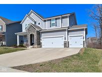 Charming two-story home boasts a large driveway and a two-car garage, complemented by stone accents and a well-maintained lawn at 655 Bracknell Dr, Avon, IN 46123