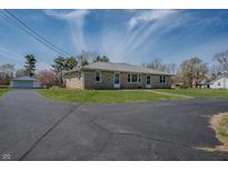 Well-maintained ranch-style home with a lush green lawn and a long, paved driveway at 6954 S Jonesville Rd, Columbus, IN 47201