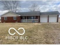 Ranch-style home with a brick facade, a covered porch, and an attached two-car garage at 7950 N 475 E, Columbus, IN 47203