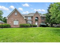 Beautiful two-story brick home featuring manicured landscaping and a lush green lawn on a sunny day at 12307 Pebblepointe Pass, Carmel, IN 46033