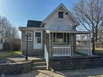 Charming home featuring a covered front porch with white picket fence and a well-lit exterior at 2025 George St, Anderson, IN 46016