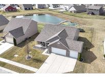 Aerial view of home with pond and fenced yard, featuring a well-manicured lawn and a two-car garage at 4324 Stubbington Ln, Indianapolis, IN 46239