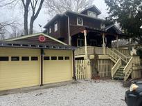 Charming brown two-story home with a large porch and detached two car garage at 5140 Riverview Dr, Indianapolis, IN 46208