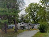 A charming home featuring mature trees with an attached basketball hoop in the driveway at 618 S Tibbs Ave, Indianapolis, IN 46241