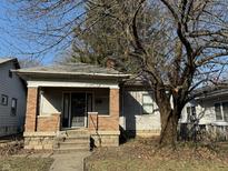 Charming single-story home featuring a brick-pillared front porch and mature shade tree at 934 N Denny St, Indianapolis, IN 46201