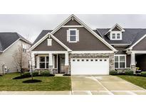 Charming home featuring brown siding, stone accents, a two-car garage and well-manicured lawn at 17099 Cole Evans Dr, Noblesville, IN 46060