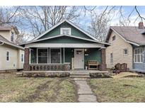 Charming green home with a covered front porch, brick accents, and well-manicured landscaping at 2135 N Dexter St, Indianapolis, IN 46202