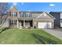 Charming two-story brick home with a well-manicured lawn and attached two-car garage on a sunny day at 281 Dovetree Dr, Danville, IN 46122