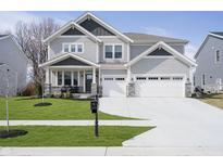 Charming two-story home featuring gray siding, stone accents, a well-manicured lawn, and a three-car garage at 19966 Chatham Green Dr, Westfield, IN 46074