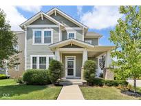 Charming two-story home with a covered porch and landscaped front yard and green horizontal siding at 5944 Aldridge Dr, Whitestown, IN 46075