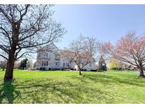 Beautiful two-story home with a stone facade, lush green lawn, and mature trees under a clear blue sky at 9921 N Wind River Run, McCordsville, IN 46055