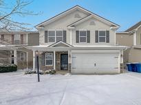 Two story home featuring stone accents, gray siding and an attached two car garage with snow on the lawn at 15503 Sandlands Cir, Noblesville, IN 46060