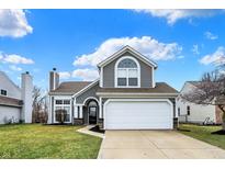 Charming home featuring gray siding, a manicured lawn, and an attached two-car garage at 17919 Grassy Knoll Dr, Westfield, IN 46074