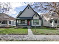 Charming two-story home with a covered porch, landscaped yard, and a vibrant red front door at 2432 N Talbott St, Indianapolis, IN 46205