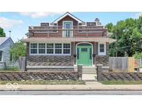 Charming two-story home features a stone facade and inviting green front door, complemented by a spacious balcony at 320 W 29Th St, Indianapolis, IN 46208