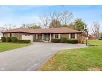 Charming brick ranch home featuring a spacious driveway, manicured landscaping, and a welcoming teal-colored front door at 3602 N County Road 950 E, Brownsburg, IN 46112