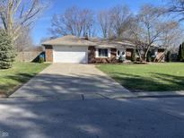 Charming brick home featuring an attached garage and long driveway situated on a well-maintained lawn at 4252 Bittersweet Ln, Greenwood, IN 46142
