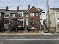 Three, two-story brick and painted-wood townhomes are featured in this exterior view at 614 E 11Th St, Indianapolis, IN 46202