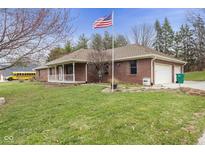 Charming brick home with an American flag, manicured lawn, and attached two-car garage at 12129 N Cedarview Dr, Mooresville, IN 46158