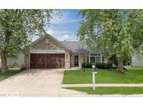 Charming brick home with a well-maintained lawn, a two car garage and mature trees at 136 Meadow Glen Dr, Avon, IN 46123