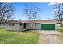 Charming single-story home features a green garage door, a well-maintained lawn, and mature trees at 1620 S East St, Lebanon, IN 46052