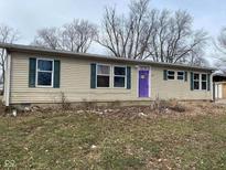 Tan single-story home featuring green shutters and a purple front door at 209 Crawford St, Clayton, IN 46118