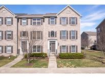 A lovely three story tan brick townhome with symmetrical windows and a manicured lawn at 253 Coatsville Dr, Westfield, IN 46074