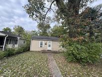 A charming single-story home has a beige exterior and small front entry surrounded by mature trees at 2820 N Gladstone Ave, Indianapolis, IN 46218