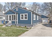 Charming blue home featuring a well-maintained yard and a detached one car garage at 4929 Ralston Ave, Indianapolis, IN 46205