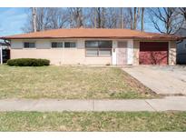 Ranch-style home featuring vinyl siding, a red garage door, and a well-maintained front yard at 6724 E 52Nd St, Indianapolis, IN 46226