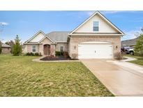 Charming brick home with a well-manicured lawn and attached two-car garage in a suburban neighborhood at 7236 Sunset Point Dr, Indianapolis, IN 46259