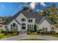 Stunning white home featuring lush landscaping, a circular drive, and beautiful architectural details at 10415 Charter Oaks, Carmel, IN 46032