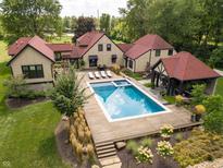 Beautiful aerial view of pool with wooden deck, lounge chairs, covered outdoor kitchen and well-manicured landscaping at 11022 E 116Th St, Fishers, IN 46037
