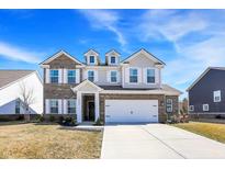 Beautiful two-story brick home with a white garage door, manicured lawn, and a clear blue sky at 16406 Ketton Dr, Noblesville, IN 46060